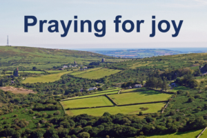 View of Cornish landscape towards Caradon Hill and the sea with caption Praying for Joy